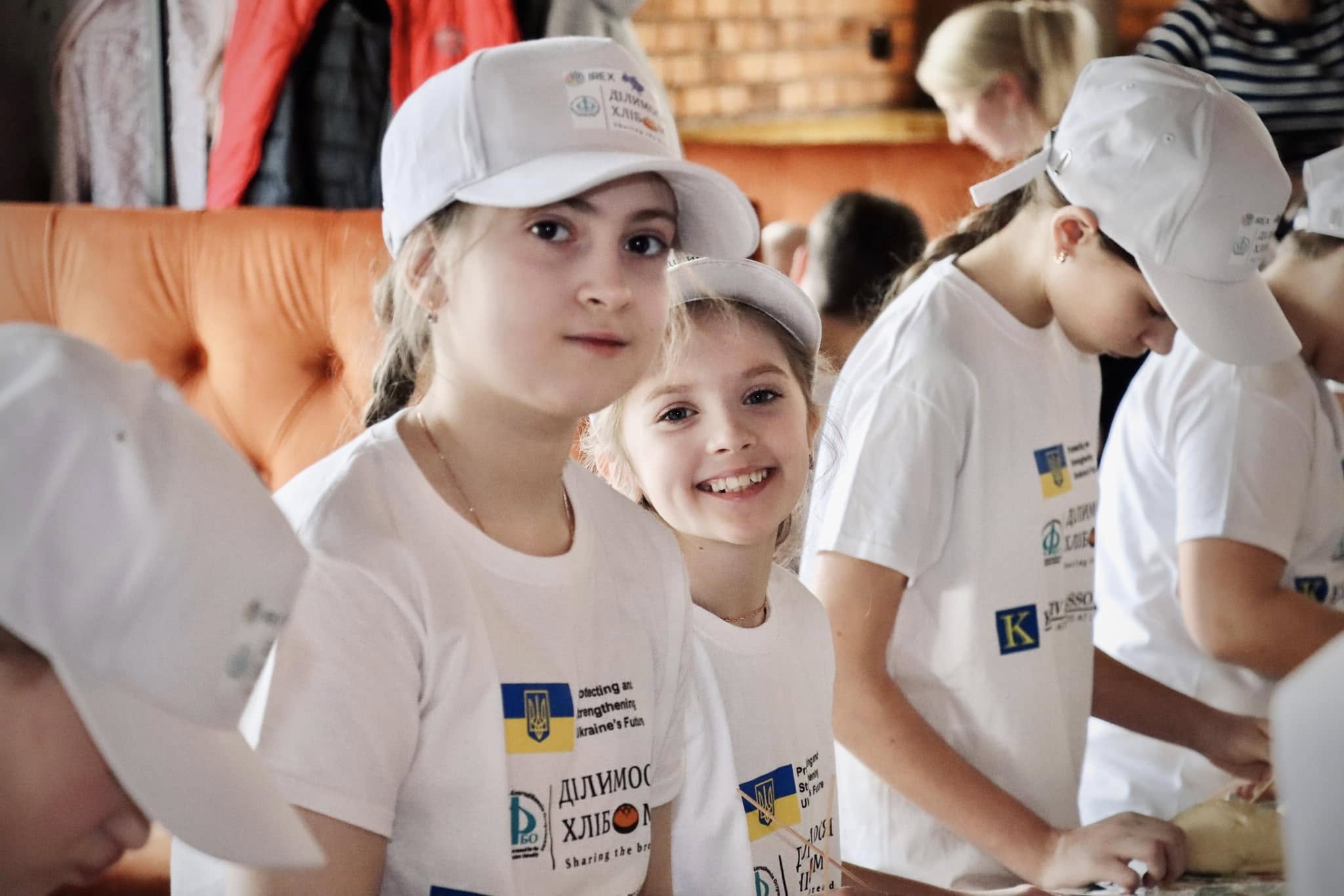 Діти у футболках посміхаються.
